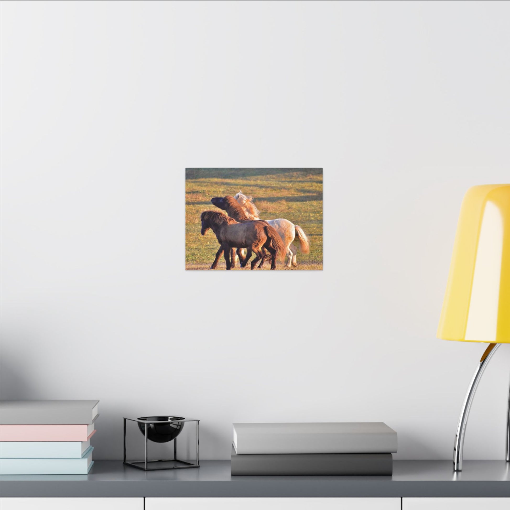Canvas print of three horses on a grassy field hanging on a wall above a desk.